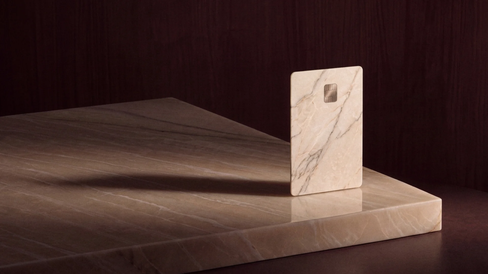 A marble card standing on a polished marble slab in low, warm light.