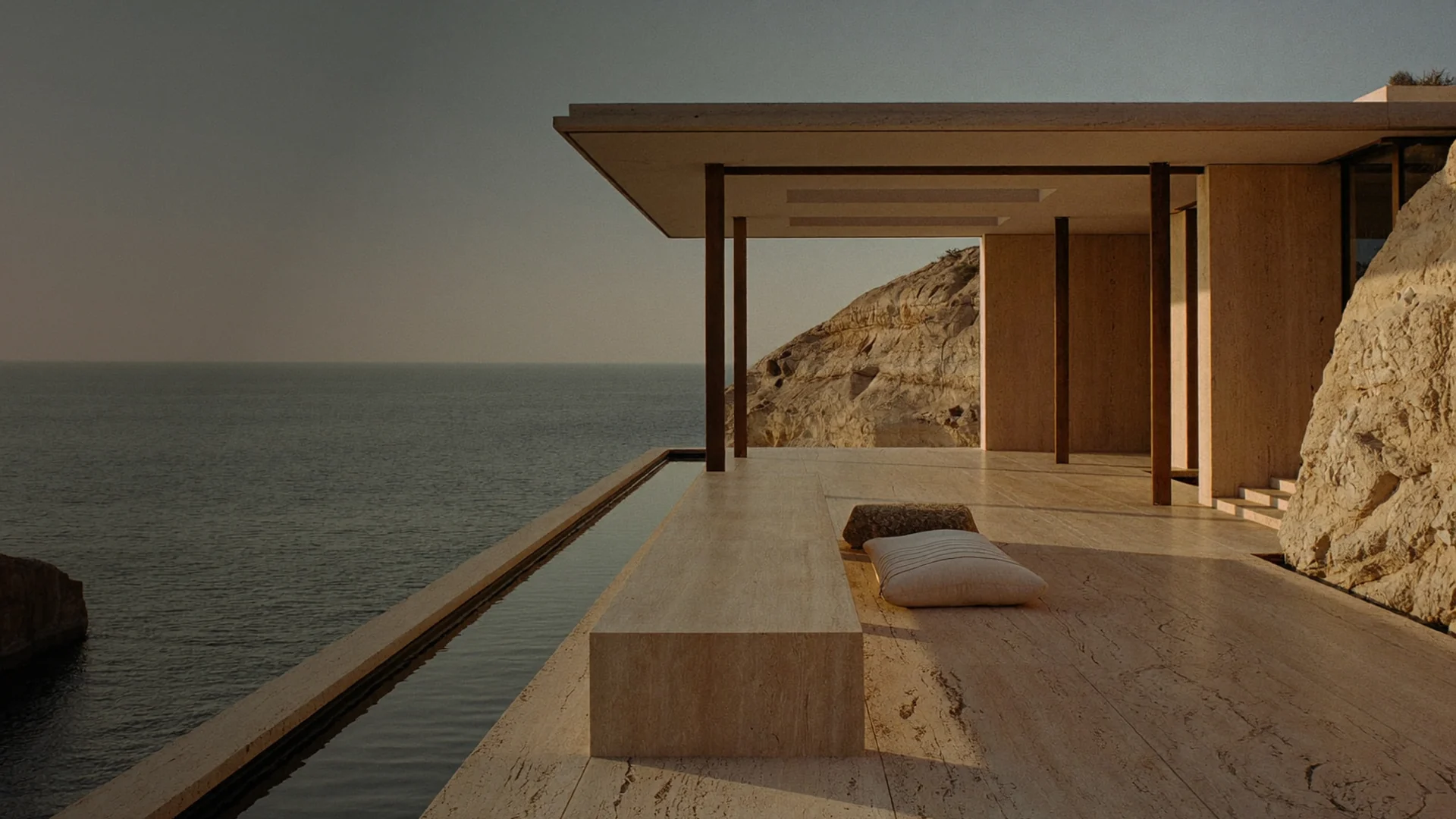 A travertine pavilion on a cliff above the sea at dusk.